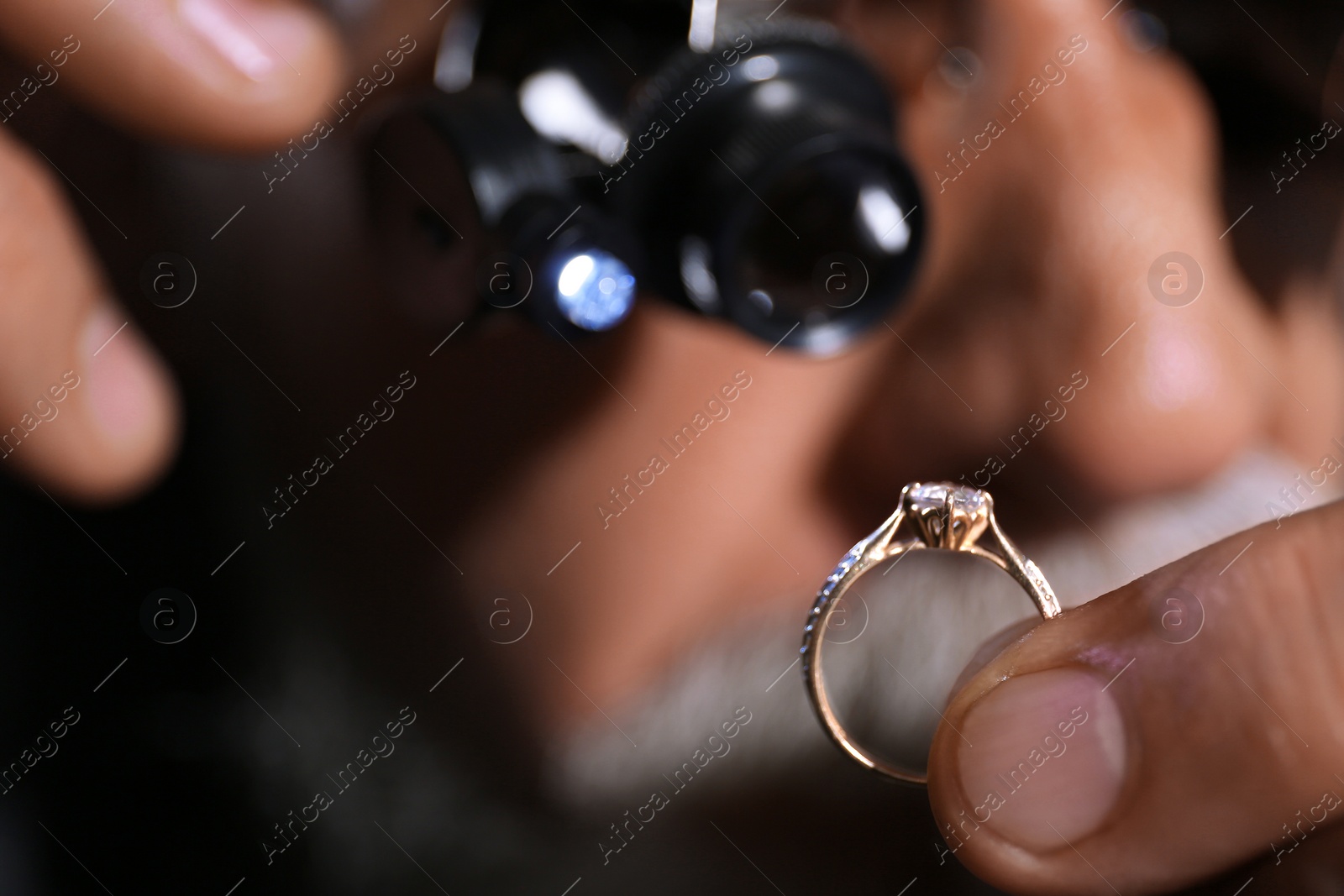 Photo of Male jeweler examining diamond ring in workshop, closeup view
