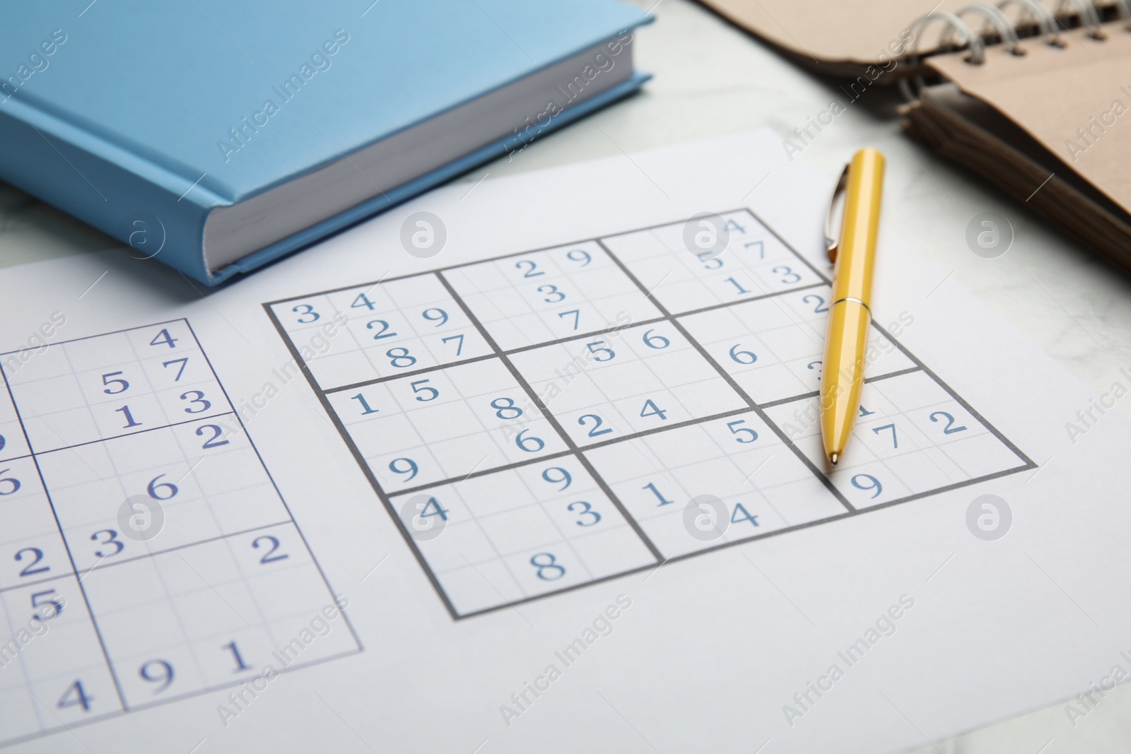 Photo of Sudoku, pen and planner on white table, closeup