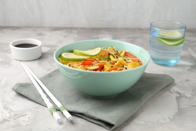 Photo of Stir-fry. Delicious cooked noodles with chicken and vegetables in bowl served on gray textured table