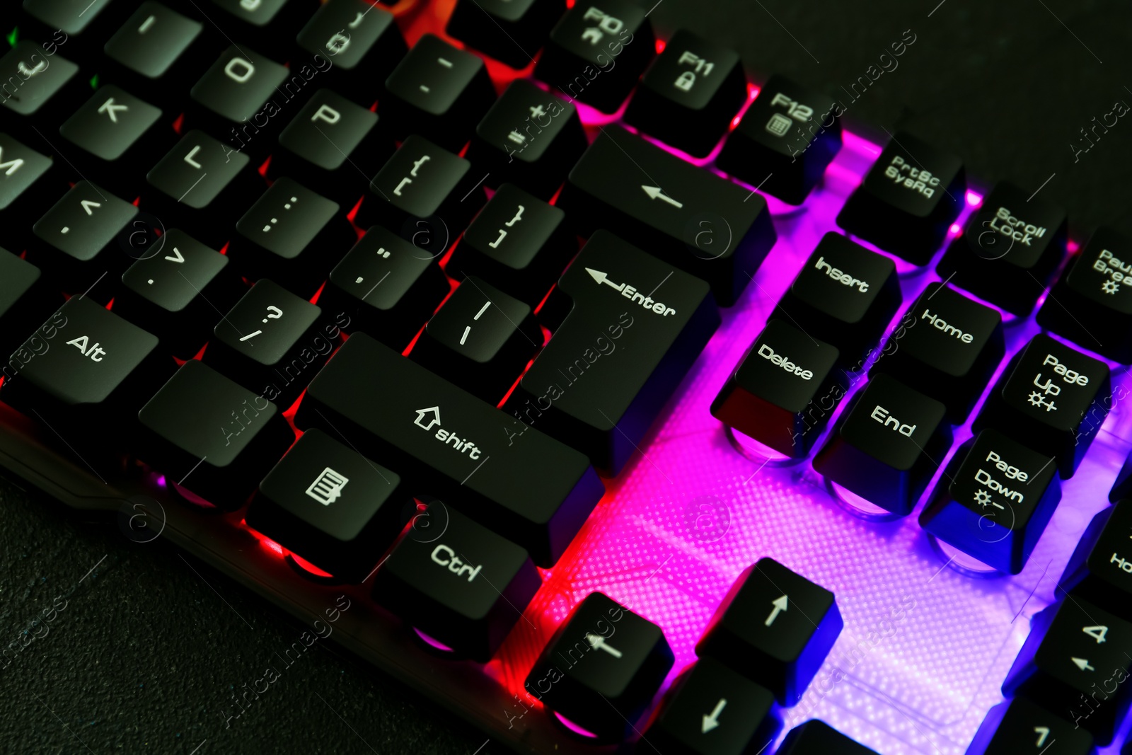 Photo of Modern keyboard with RGB lighting on black table, closeup