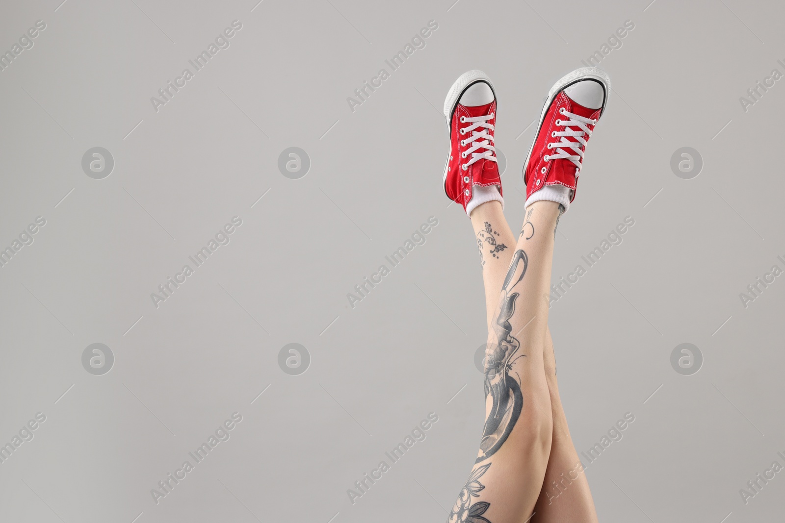 Photo of Woman with cool tattoos on grey background, closeup. Space for text