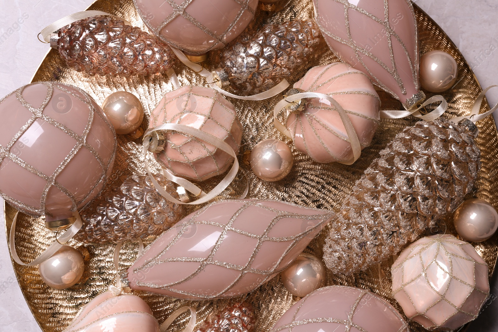 Photo of Christmas baubles on golden plate, top view