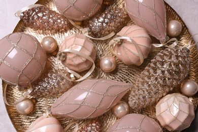 Photo of Christmas baubles on golden plate, top view