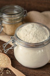 Photo of Jar with quinoa flour and seeds on wooden table