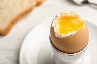 Photo of Holder with soft boiled egg on table, closeup. Space for text