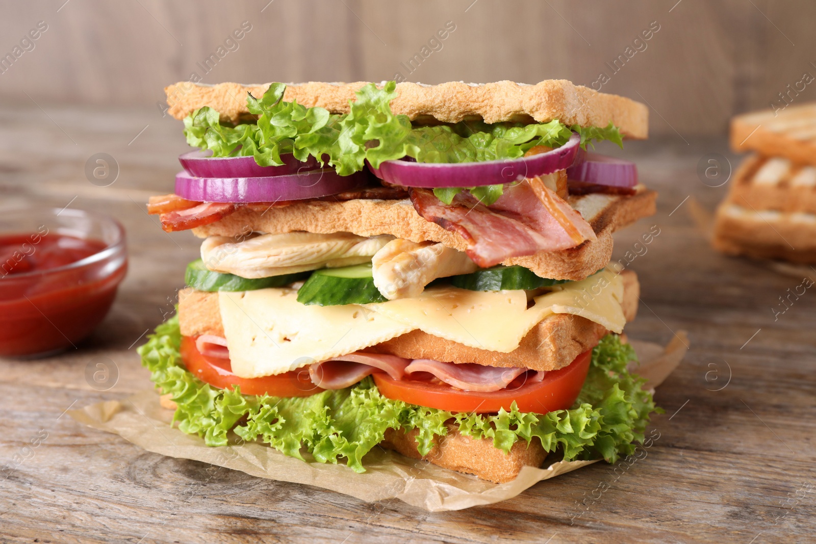 Photo of Tasty sandwich with chicken, ham and bacon  on wooden table