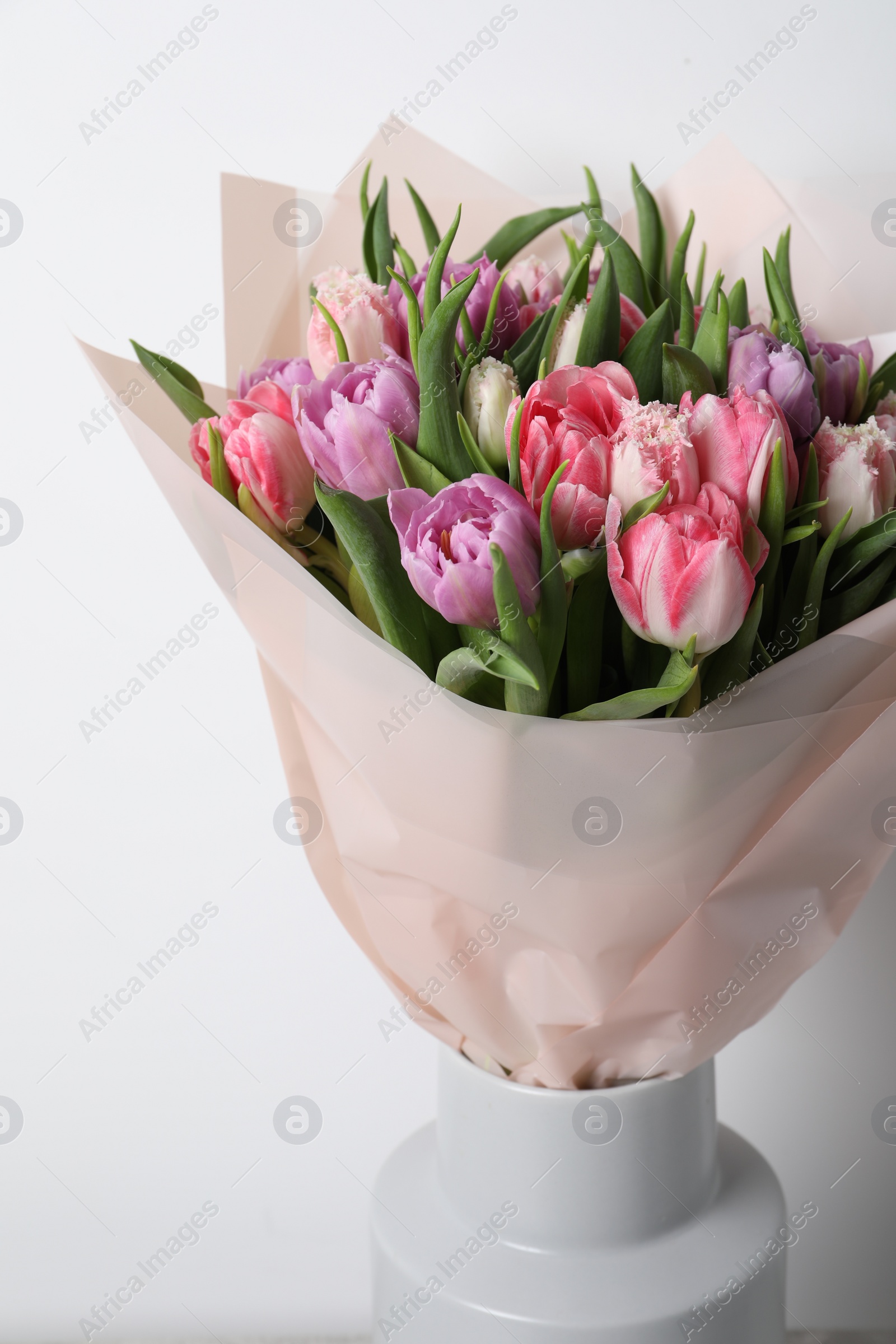 Photo of Vase with bouquet of beautiful tulips on white background, closeup