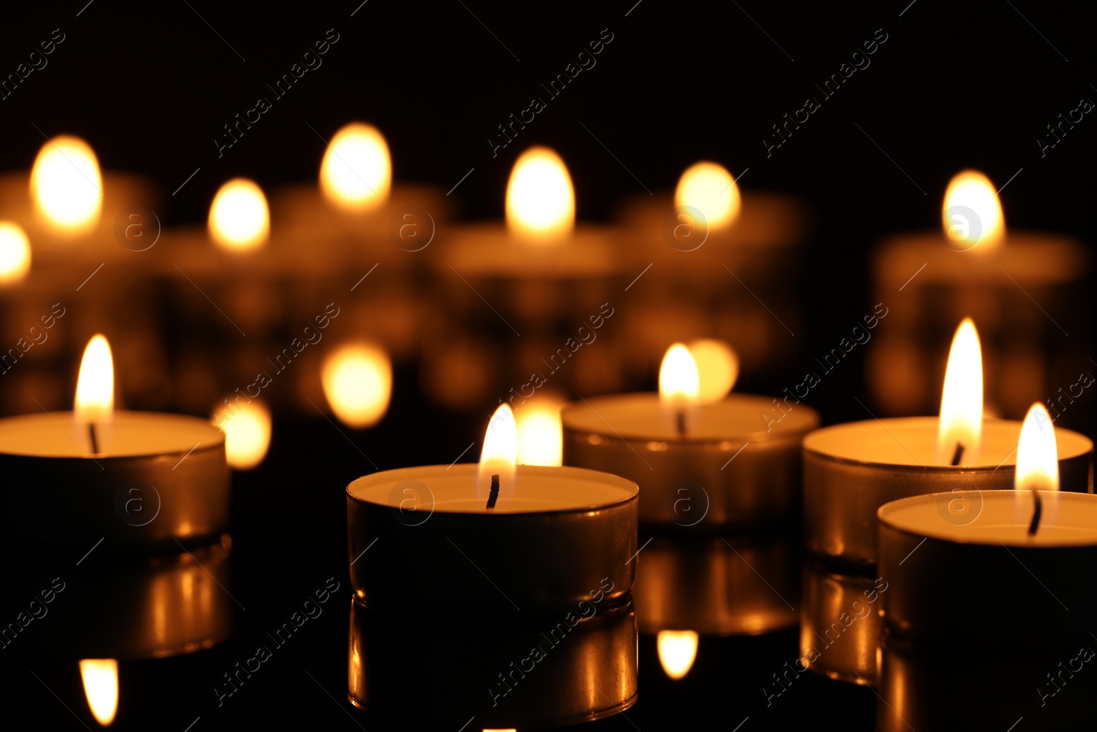 Photo of Burning candles on surface in darkness, closeup