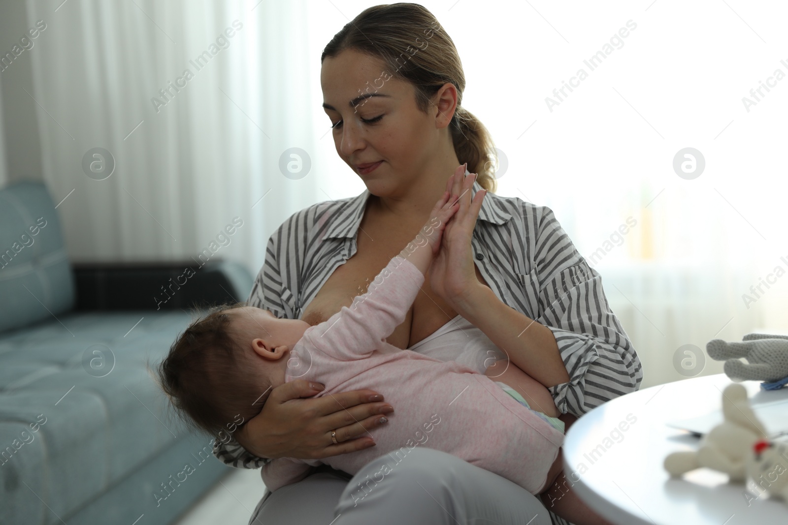 Photo of Young woman breastfeeding her baby at home