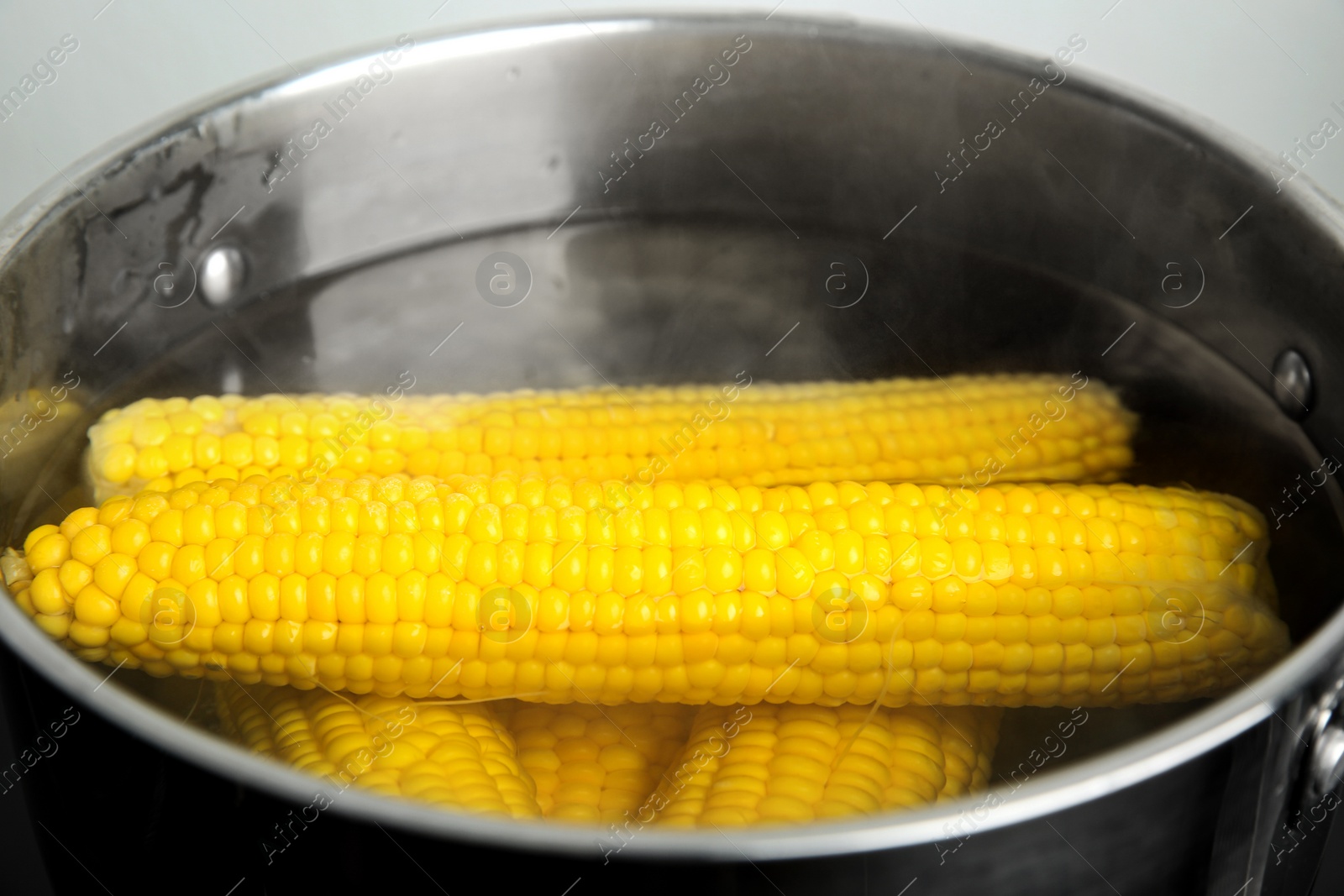 Photo of Pan with boiling corns in hot water, closeup