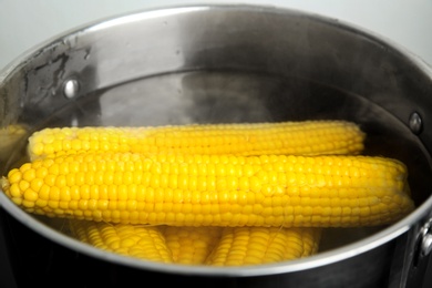 Photo of Pan with boiling corns in hot water, closeup