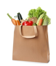 Photo of Paper bag with vegetables and bottle of juice on white background