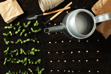 Photo of Gardening tools, corn seeds and vegetable seedlings in fertile soil, flat lay