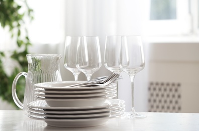 Photo of Set of clean dishes, cutlery and glassware on table indoors