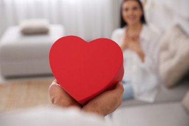 Man presenting gift to his beloved woman at home, closeup. Valentine's day celebration