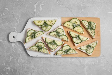 Photo of Tasty sandwiches with cream cheese, cucumber and dill on grey marble table, flat lay