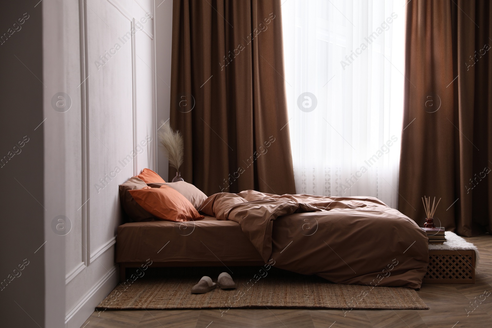 Photo of Bed with orange and brown linens in stylish room