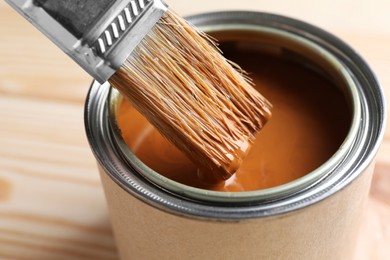 Photo of Dipping brush into can with wood stain on table, closeup