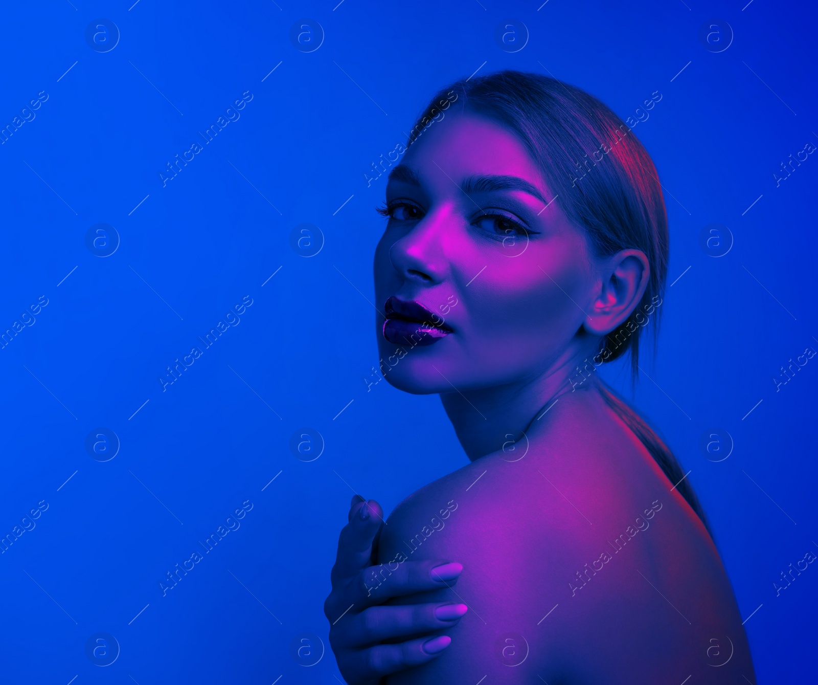 Image of Young woman with beautiful makeup posing in neon lights against blue background