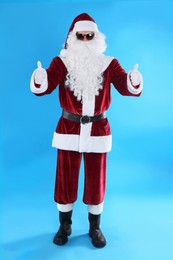 Photo of Full length portrait of Santa Claus with sunglasses on light blue background