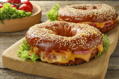 Photo of Delicious bagels with ham and cheese on wooden table