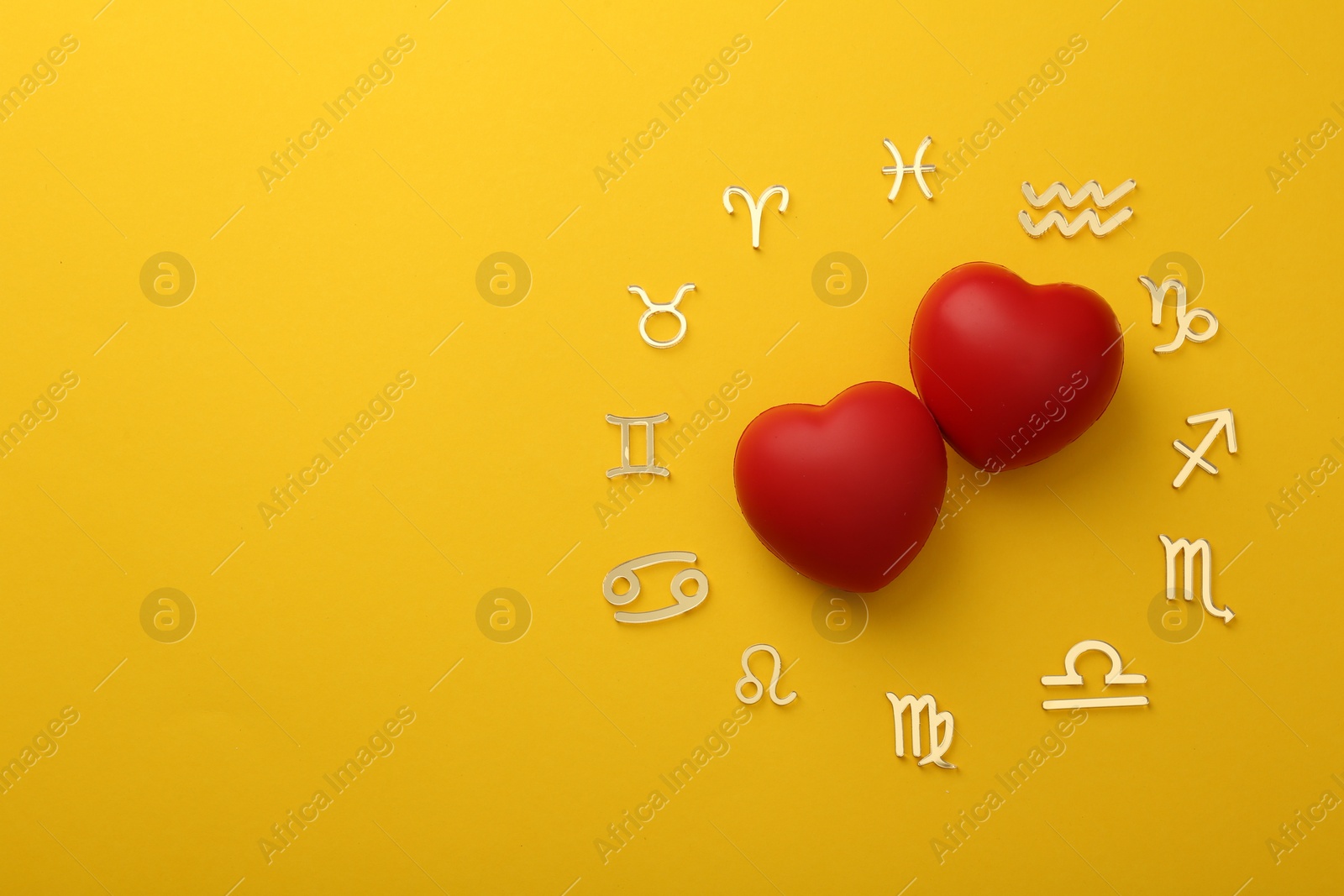 Photo of Zodiac signs and red hearts on yellow background, flat lay. Space for text