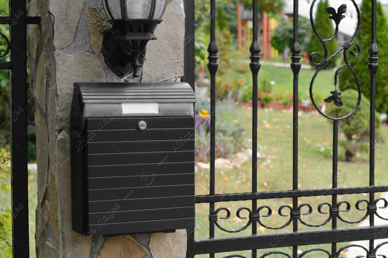 Photo of Metal letter box on stone column near fence outdoors