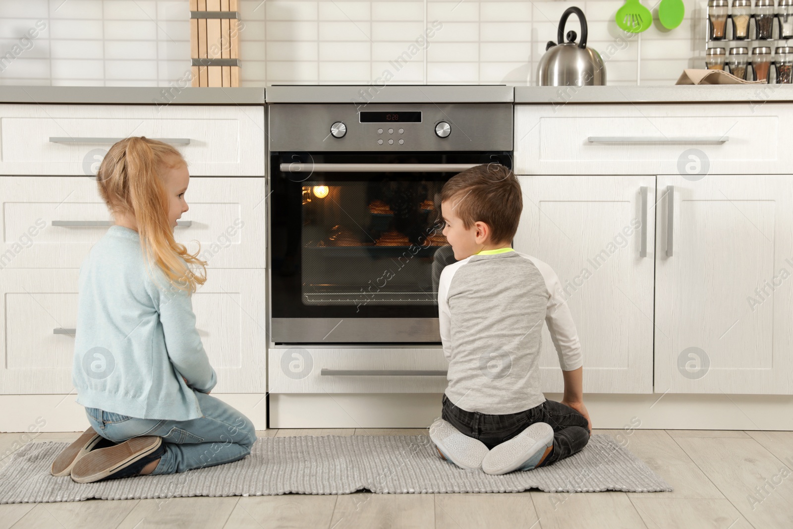 Photo of Little kids waiting for preparation of buns in oven at home