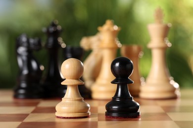 Photo of Different pawns and other chess pieces on game board against blurred background, closeup