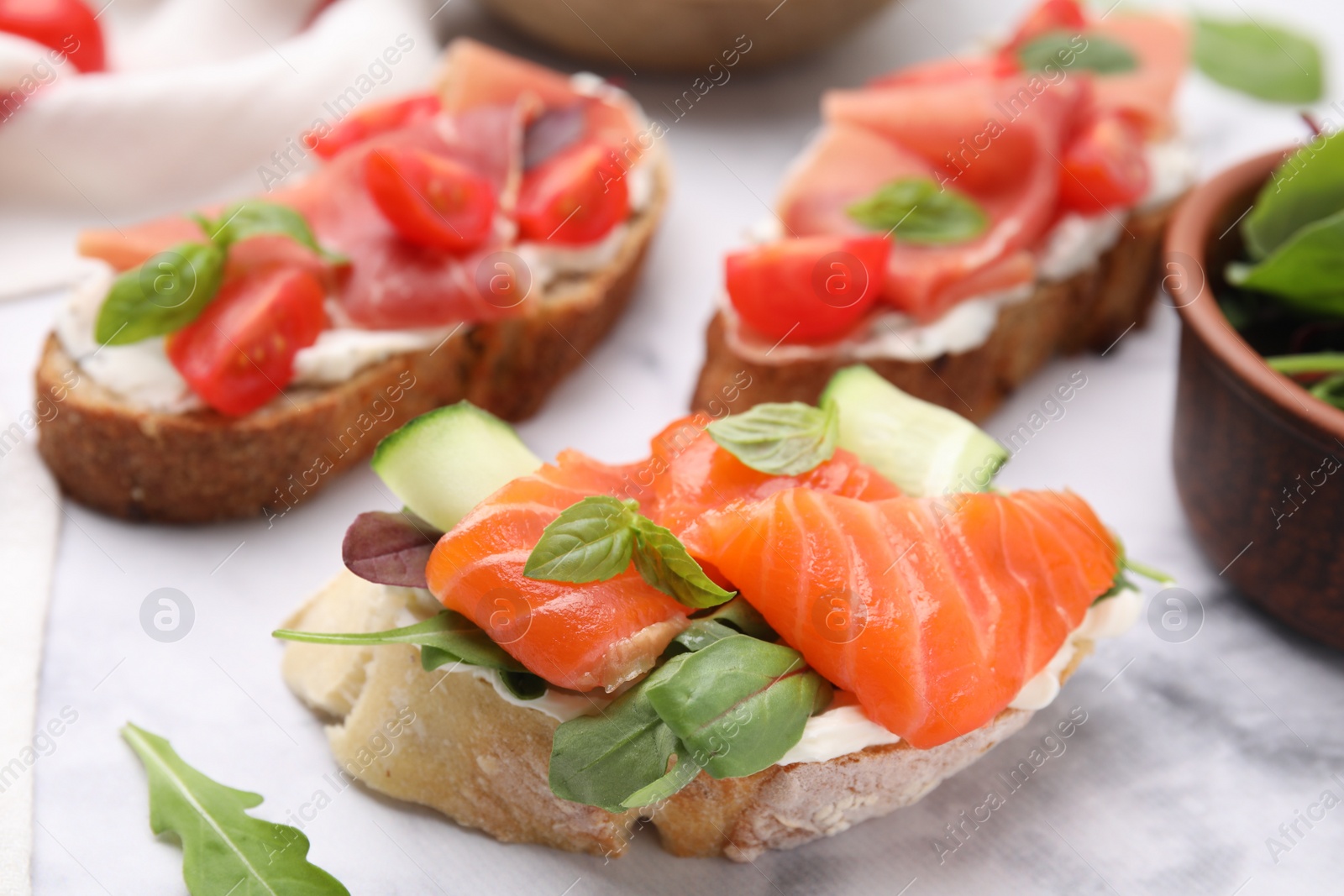 Photo of Tasty different bruschettas on white marble table, closeup