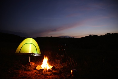 Photo of Camping tent near small bonfire at night