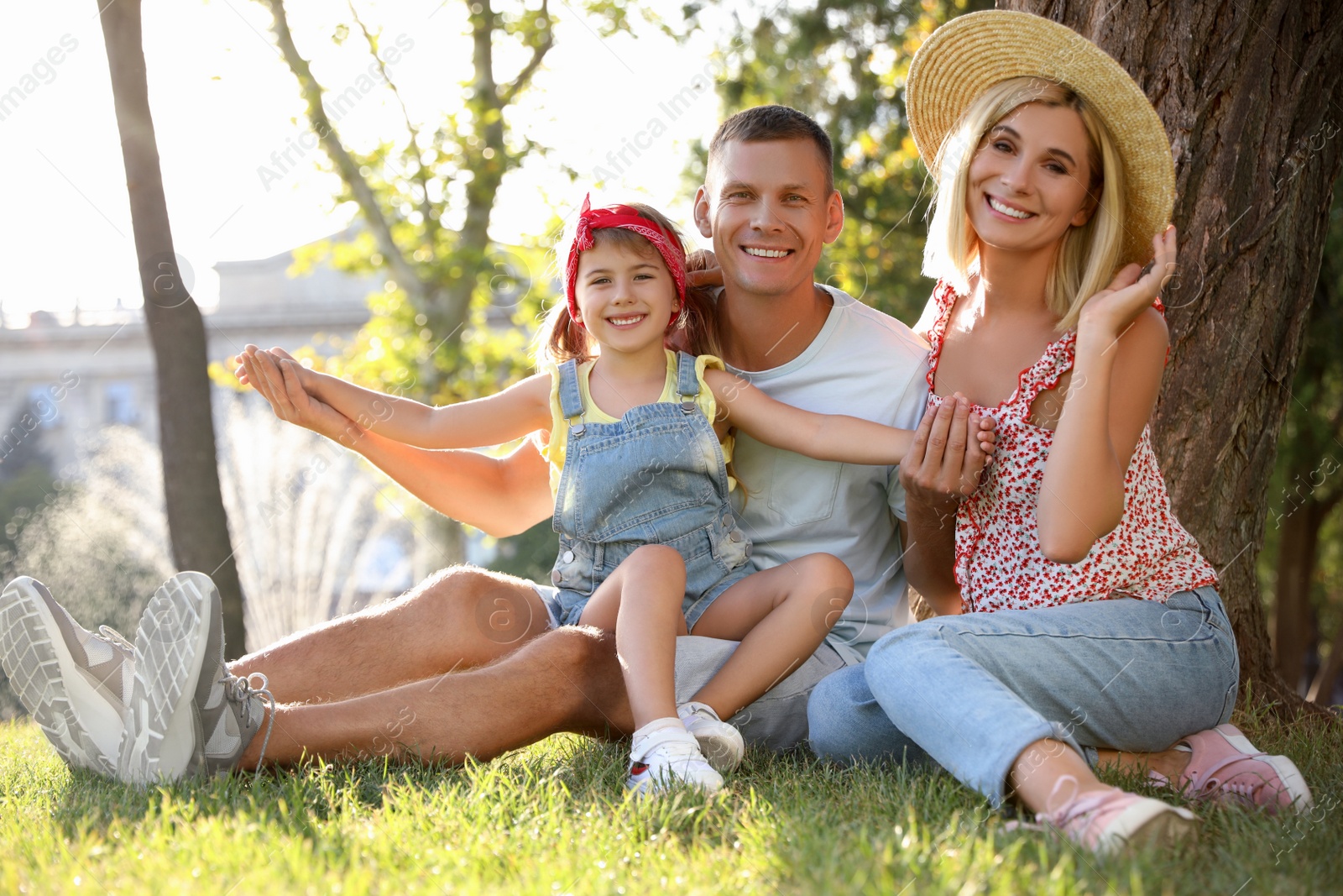 Photo of Happy parents with their child having fun on green grass. Spending time in nature