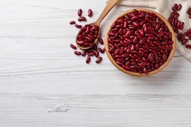 Raw red kidney beans with bowl and spoon on white wooden table, flat lay. Space for text