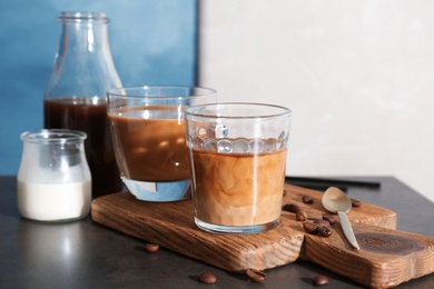 Photo of Glasses with cold brew coffee and milk on wooden board