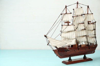 Photo of Beautiful ship model on light blue wooden table. Space for text