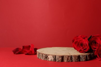 Photo of Presentation for product. Wooden podium and beautiful roses against red background, space for text