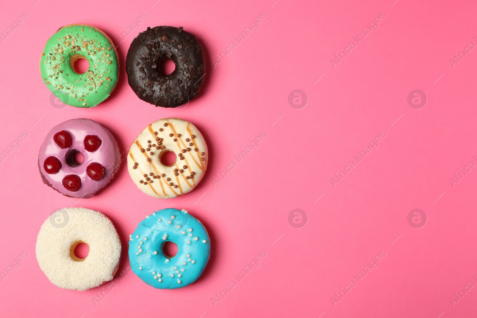 Photo of Different delicious glazed doughnuts on pink background, flat lay. Space for text
