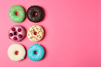 Different delicious glazed doughnuts on pink background, flat lay. Space for text