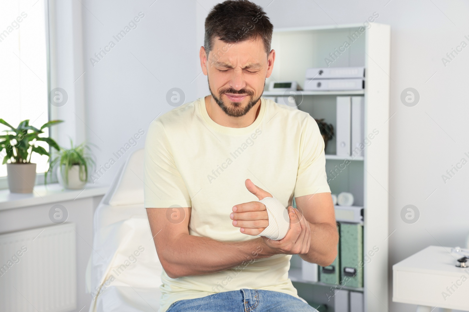 Photo of Man with hand wrapped in medical bandage at hospital