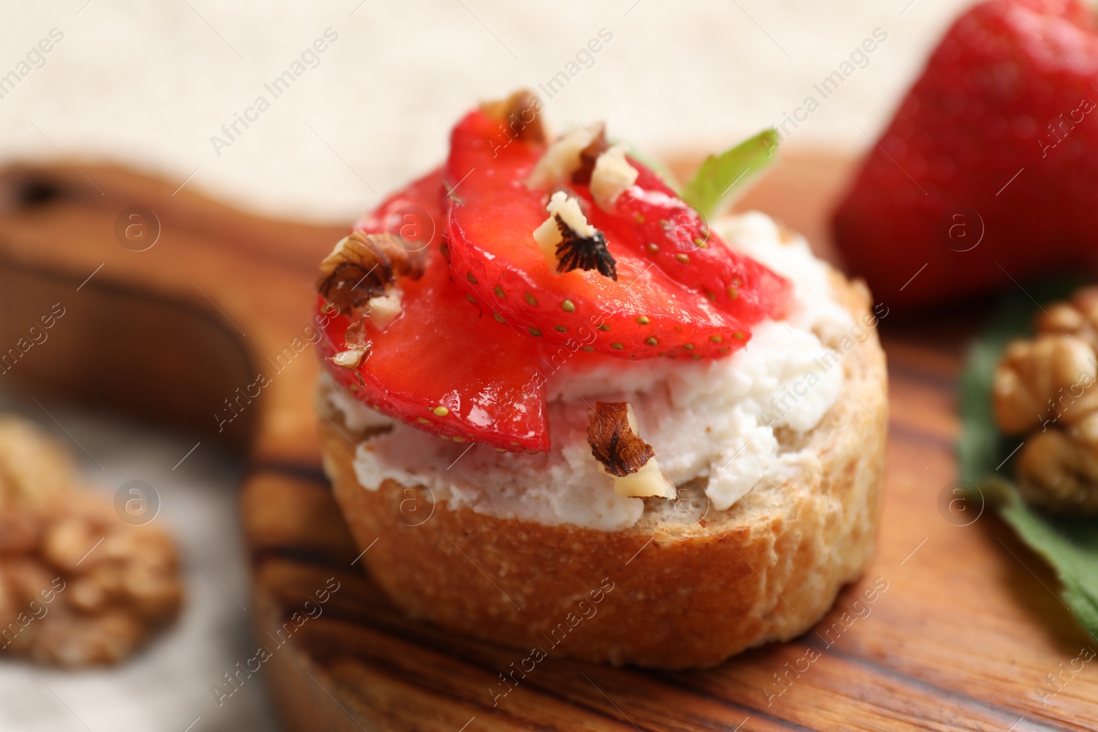 Photo of Delicious ricotta bruschetta with strawberry and walnut served on table, closeup