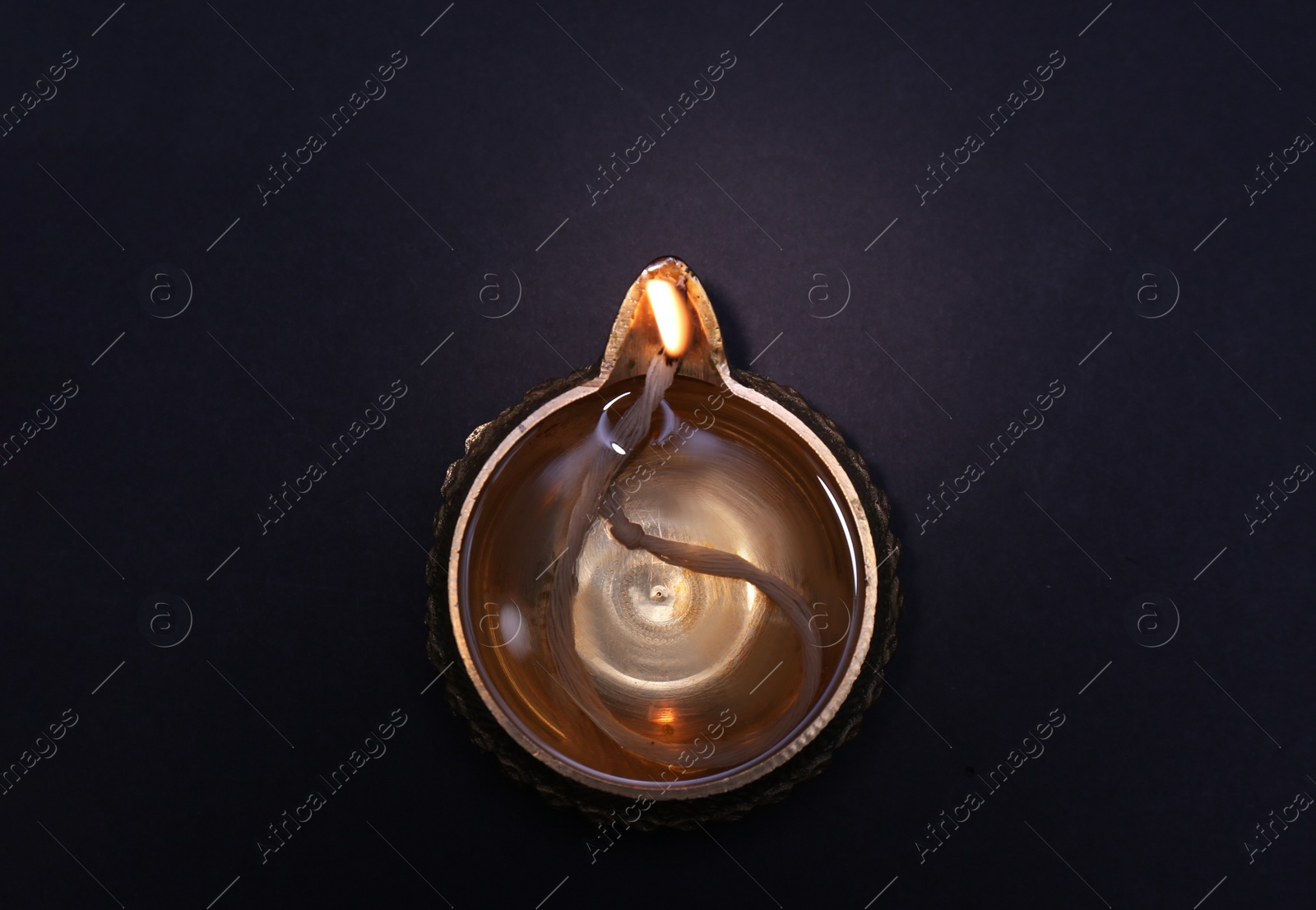 Photo of Lit diya on dark background, top view. Diwali lamp