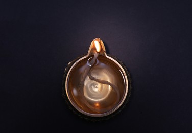 Photo of Lit diya on dark background, top view. Diwali lamp