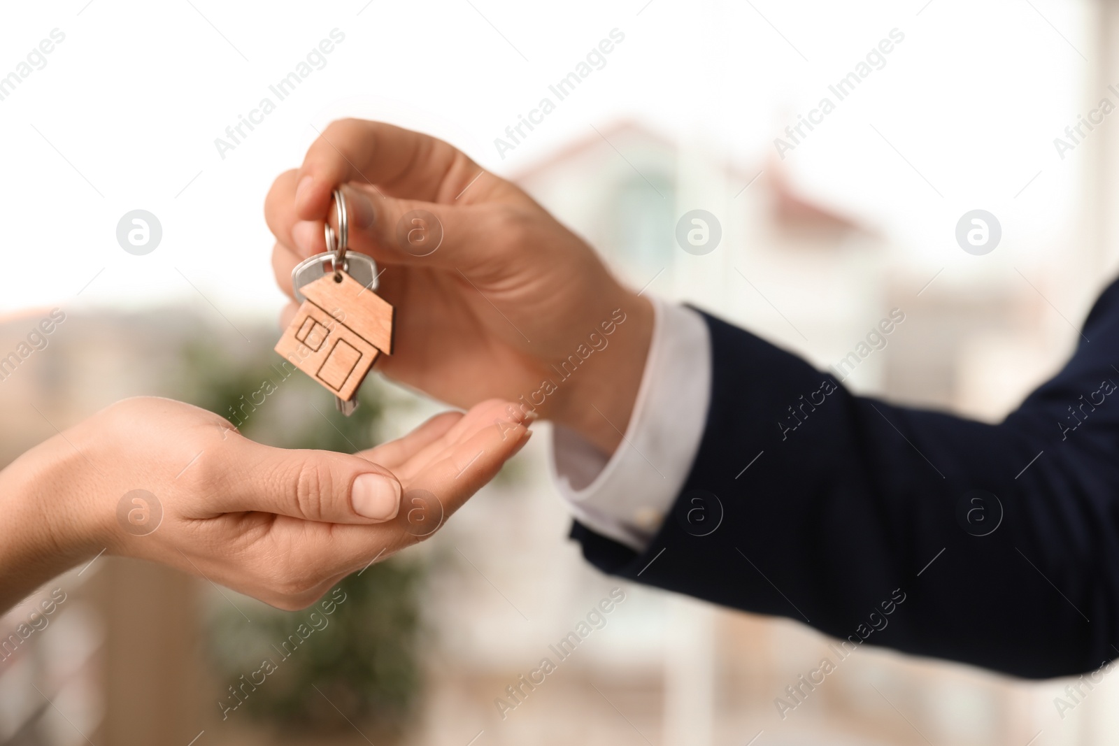 Photo of Real estate agent giving key with trinket to client in office, closeup