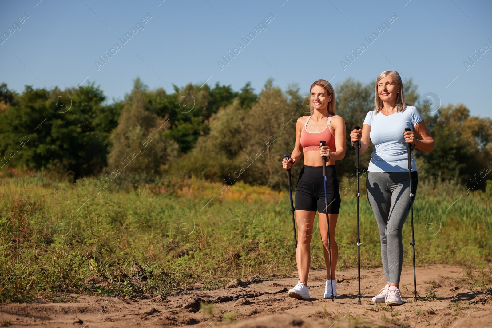 Photo of Happy women practicing Nordic walking with poles outdoors on sunny day