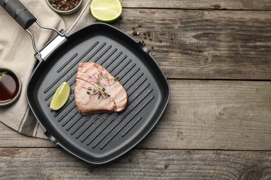 Photo of Delicious tuna steak served on wooden table, flat lay. Space for text