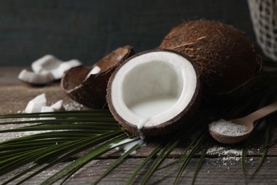 Coconut milk, flakes, nuts and palm leaf on wooden table, closeup