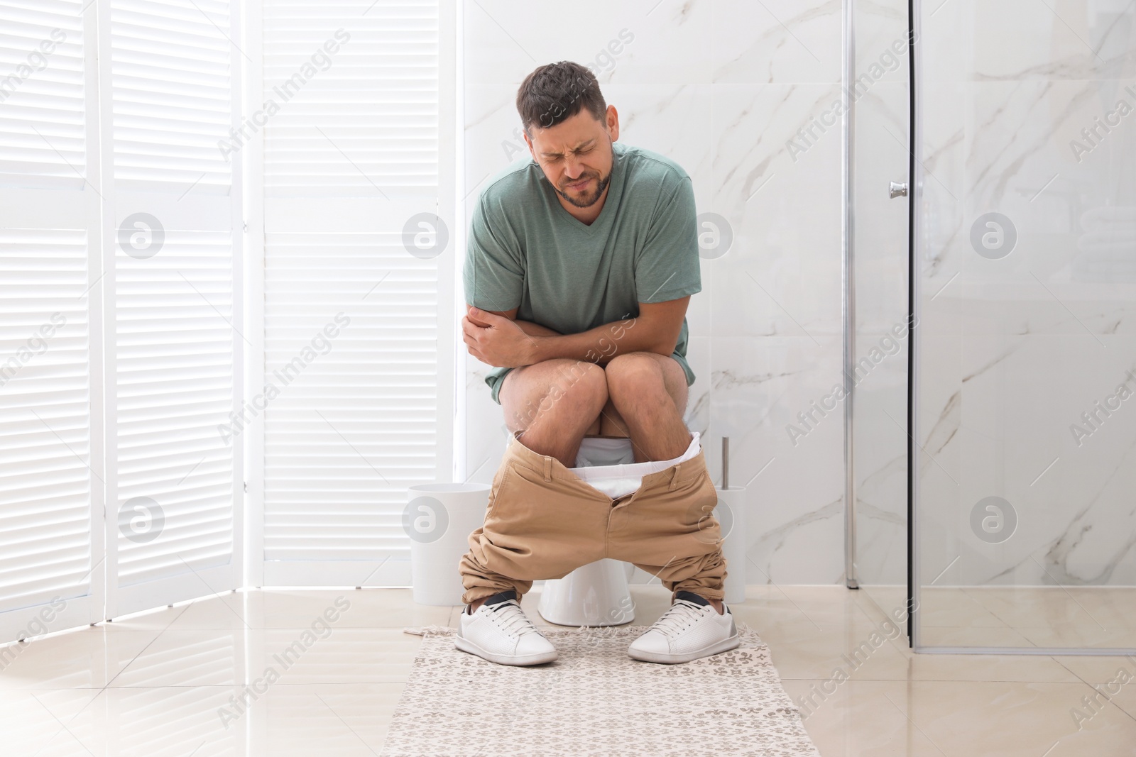 Photo of Man suffering from hemorrhoid on toilet bowl in rest room