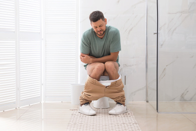 Man suffering from hemorrhoid on toilet bowl in rest room