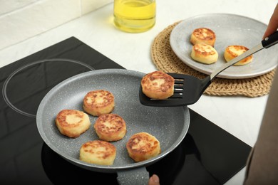 Photo of Woman frying delicious cottage cheese pancakes in kitchen, closeup