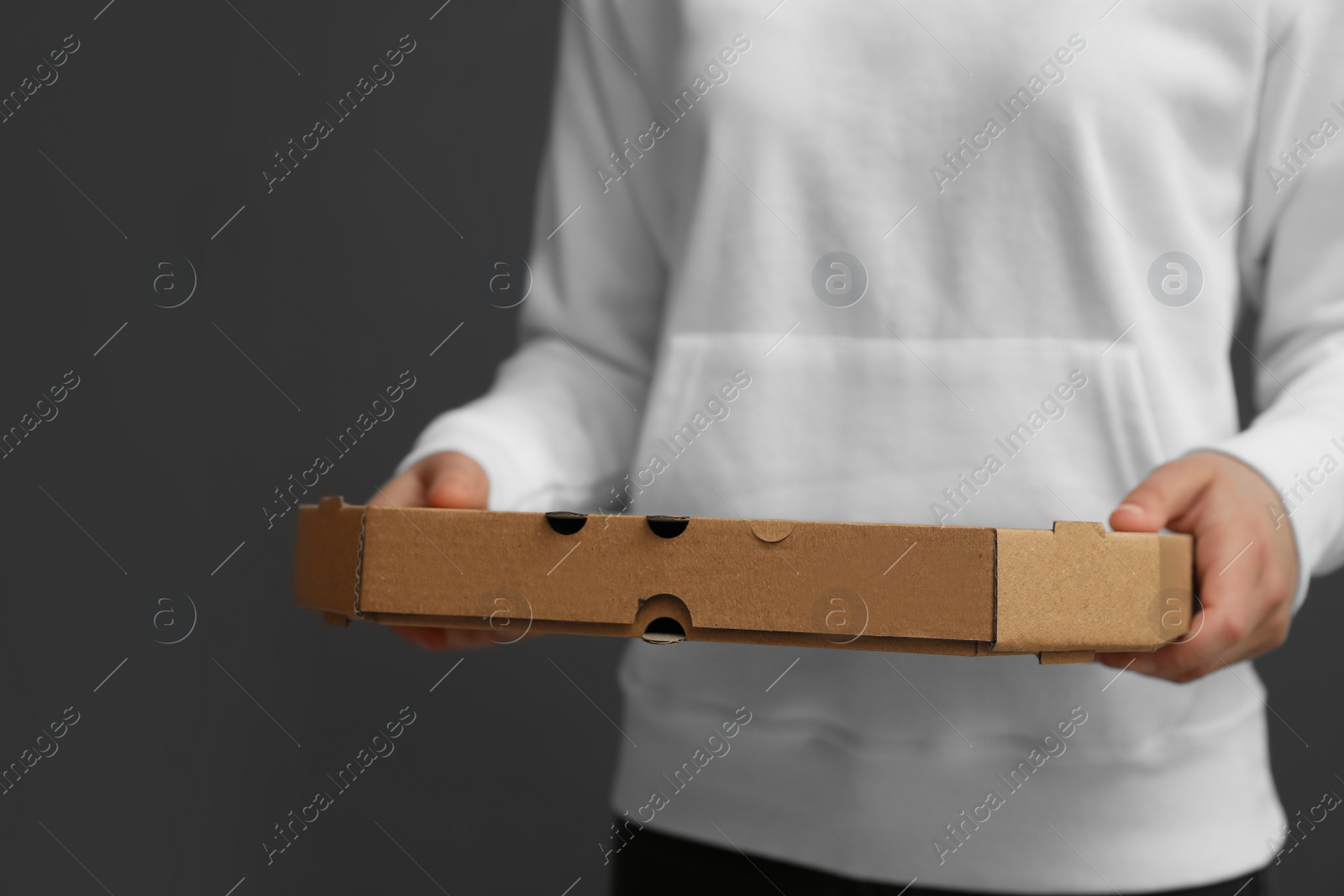 Photo of Young woman with pizza box on grey background, closeup. Food delivery service